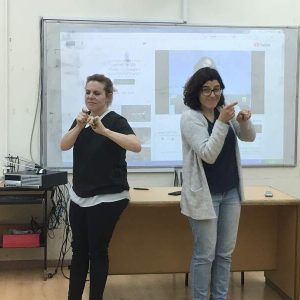 שתי נשים עומדות בחדר הרצאות, במהלך של תרגום לשפת הסימנים